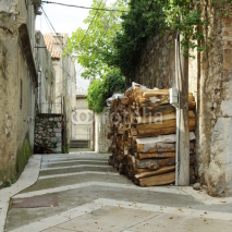 Senj, Croatia – September 18, 2016: a small town in northern Croatia, located on the Adriatic coast. Narrow street in the old town. Firewood gathered in front of the house.