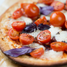 Close-up of pizza with red cherry tomatoes, mozzarella and basil