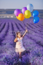 Naklejki Smiling girl sniffing flowers in a lavender field