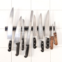 Fototapety Set of knives on magnetic holder on white tiles