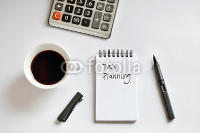 Coffee cup, spiral notebook, calculator, and pen on white backgr
