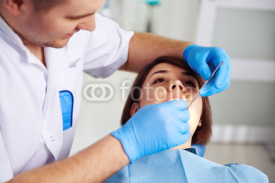 Naklejki Young woman visiting her dentist. Female patient sitting in chair in dental clinic with open mouth, taking treatment. Concept of  teeth examination and disease cure.  