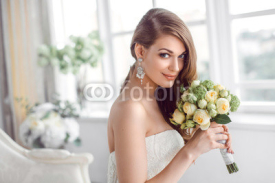 Bride in beautiful dress sitting resting on sofa indoors