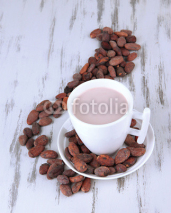 Cocoa drink and cocoa beans on wooden background