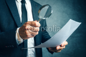 Fototapety Tax inspector investigating financial documents through magnifyi