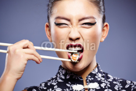 Obrazy i plakaty Sushi woman holding sushi with chopsticks looking at the camera