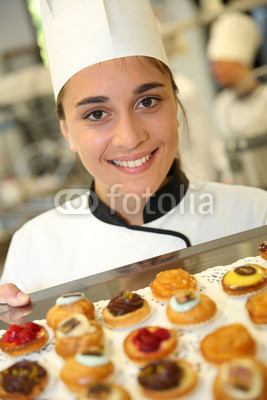 Cheerful pastry cook holding tray of pastries