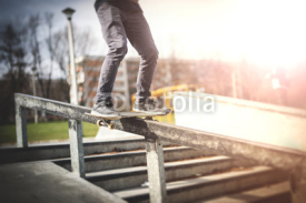 Obrazy i plakaty Skater doing frontside boardslide down the rail
