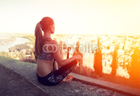 Fototapety Young woman athlete relaxing on hill peak after workout session in the evening. Concept of sport and recreation. 