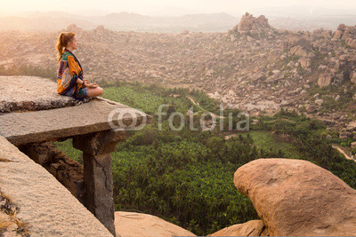 Young woman meditating at mountain cliff on sunrise