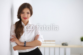Fototapety Attractive businesswoman with her arms crossed  standing in off