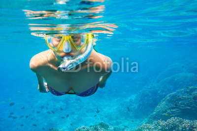 Young woman with mask snorkeling in clear tropical water