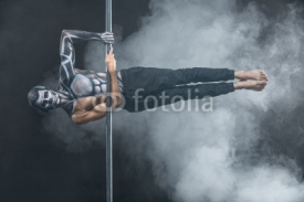Male pole dancer posing in dark studio