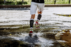 male athlete running in compression socks through a puddle water splashes