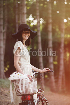 Girl on a bicycle in coniferous forest. Lightleak effect and ins