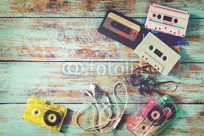 Top view (above) shot of retro tape cassette with earphone on wood table - vintage color effect styles.