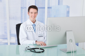 Naklejki Doctor Using Computer At Desk In Clinic