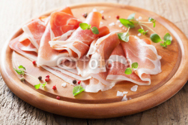 Obrazy i plakaty sliced prosciutto ham on chopping board with oregano and pepper