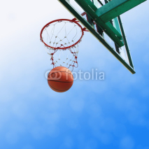 Naklejki basketball drop into the orange metal goal and white net.