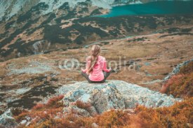 Naklejki A girl sitting on a rock and enjoying the view