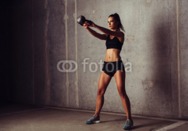 Slim attractive sportswoman in a kettlebell training