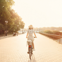 Naklejki Girl riding a bicycle in park near the lake. Lightleak effect an