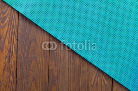 Naklejki Detail of perforated blue yoga mats on the wooden background. Texture yoga mats and boards. Boards brown. The diagonal orientation. The concept of a healthy lifestyle. Weight loss and fitness.