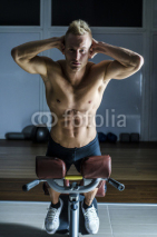 Attractive and fit young man in gym working out legs and exercising on equipment