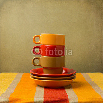 Stack of colorful coffee cups on tablecloth or place mat