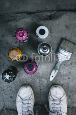 Spray paint cans and brush on sidewalk

