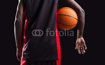 Rear view of a basketball player standing with a basket ball on