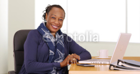 A black businesswoman poses for a portrait at her desk