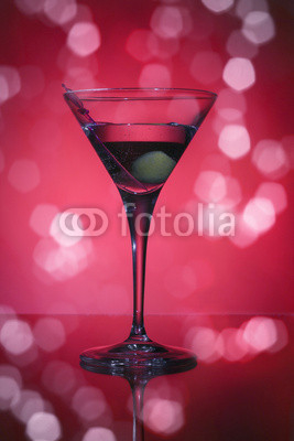 wineglass with martini and olives on red background.