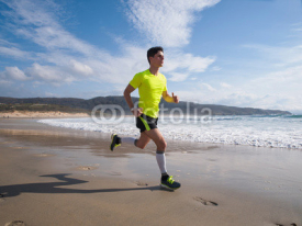 Naklejki Young Man In Fitness Clothing Running Along Beach