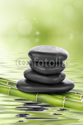Zen basalt stones on bamboo in water
