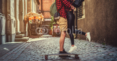 Cheerful longboarders couple posing in old town street.