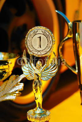Trophies for winner and yellow wheel of racing car