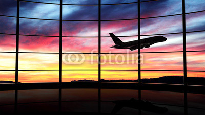 Airport window with airplane flying at sunset