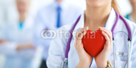 Naklejki Female doctor with stethoscope holding heart